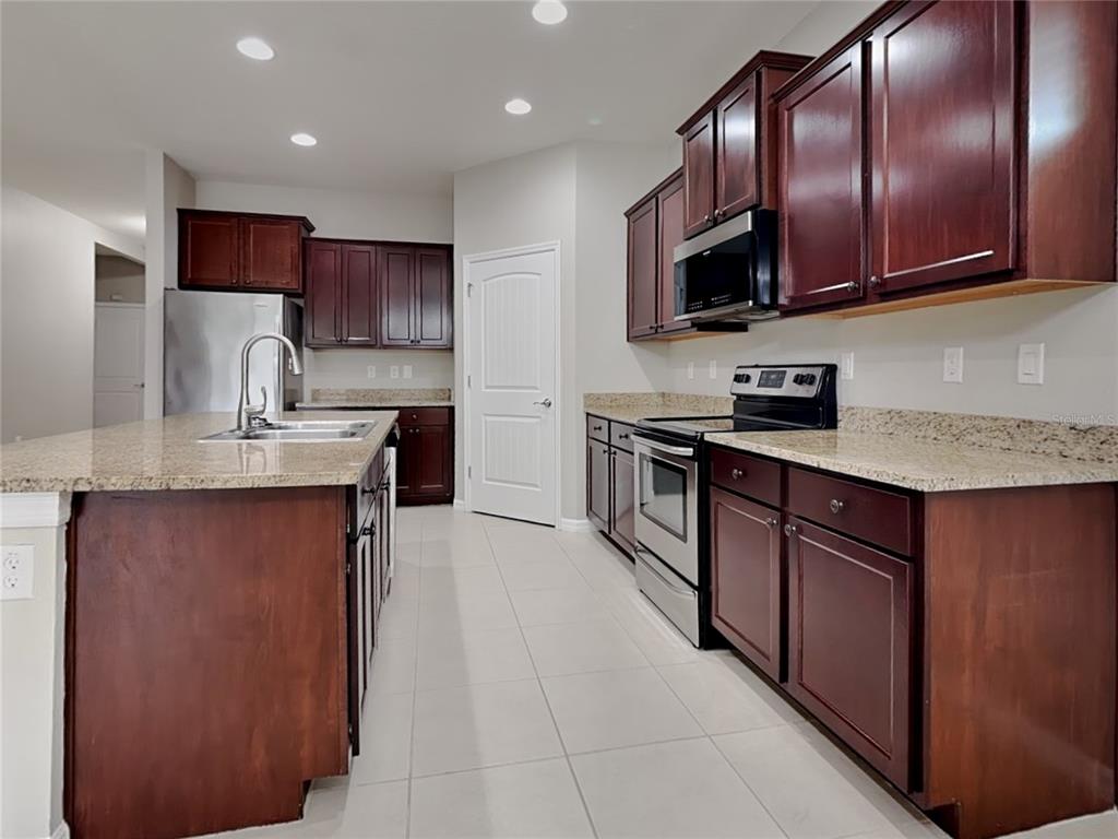 Undisclosed Address Spring Hill, FL 34609 - Photo 5 of 17 a kitchen with stainless steel appliances granite countertop a sink stove microwave and refrigerator