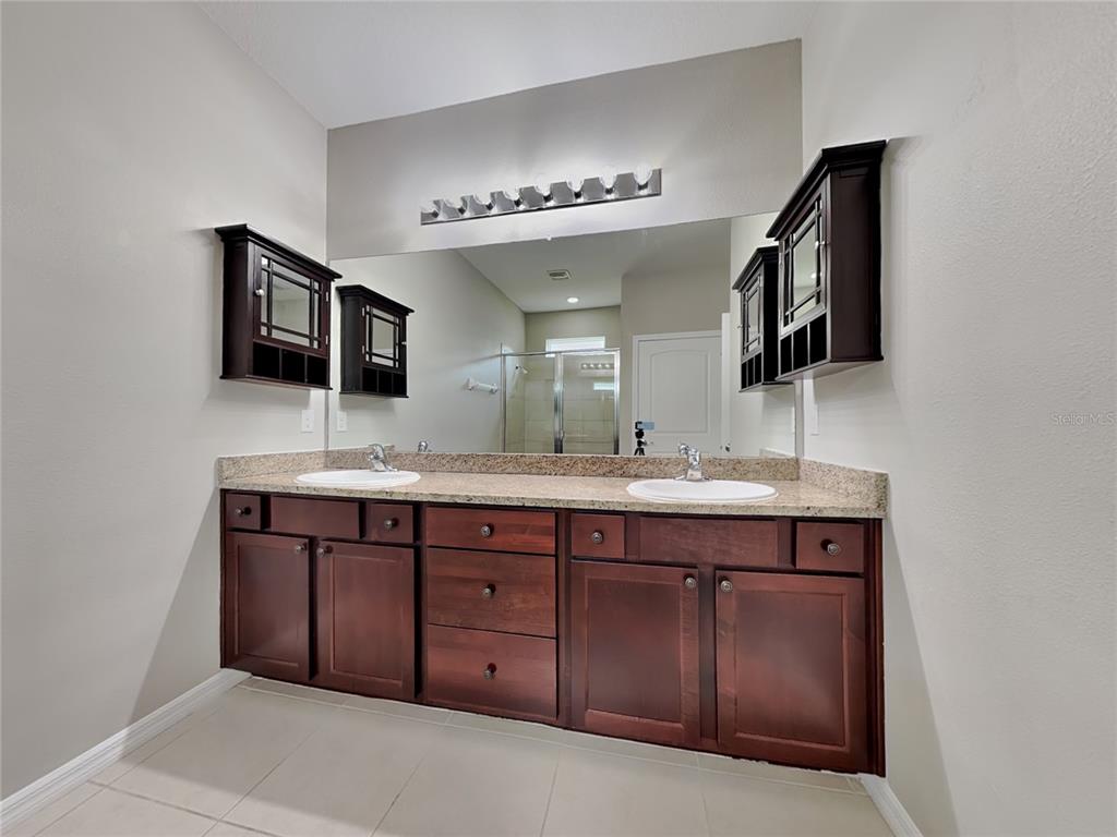 Undisclosed Address Spring Hill, FL 34609 - Photo 8 of 17 a spacious bathroom with a double vanity sink and a large mirror
