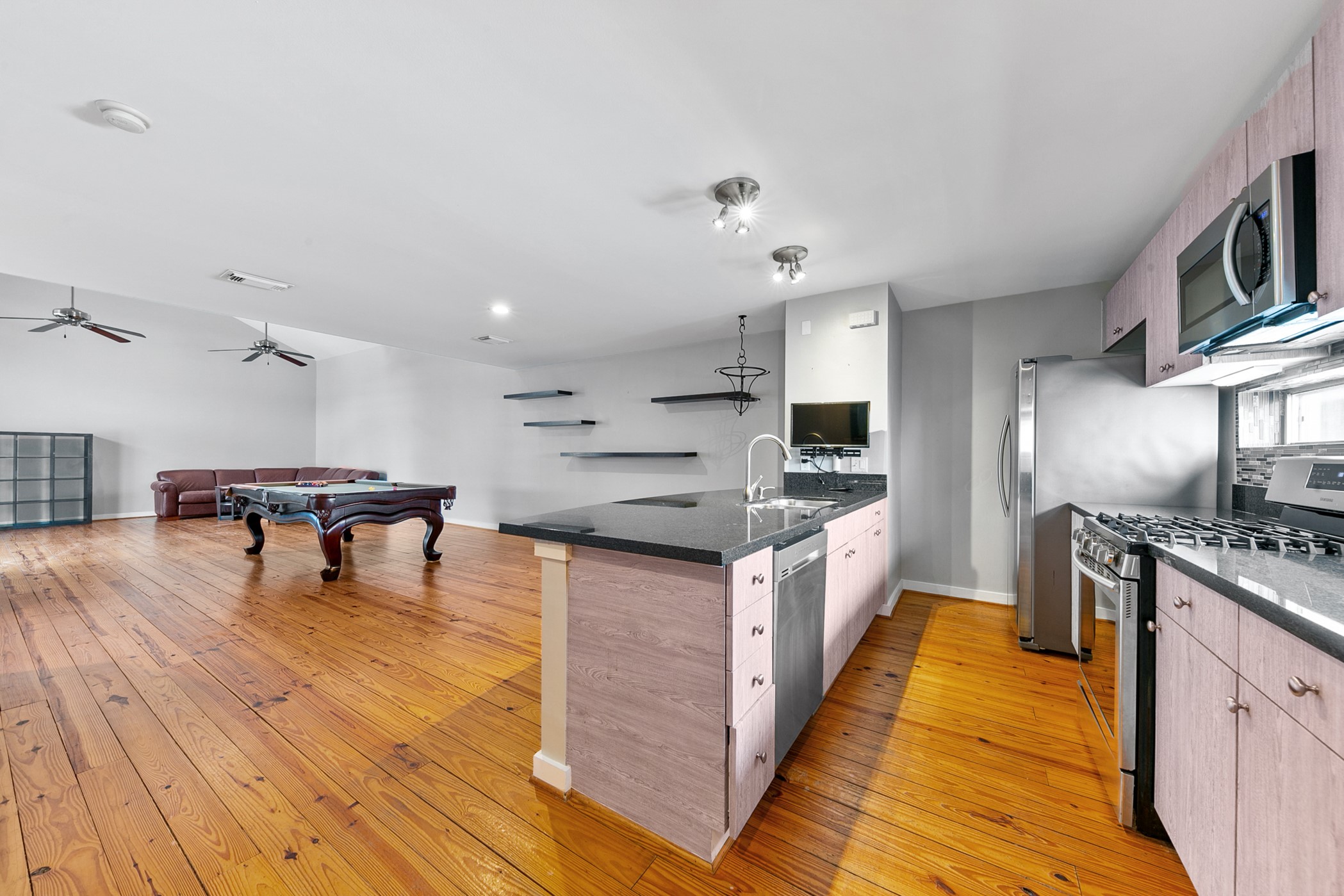 2614 Chenevert Street Houston, TX 77004 - Photo 10 of 34 a large kitchen with stainless steel appliances kitchen island granite countertop a large counter top and stove a sink with wooden floor