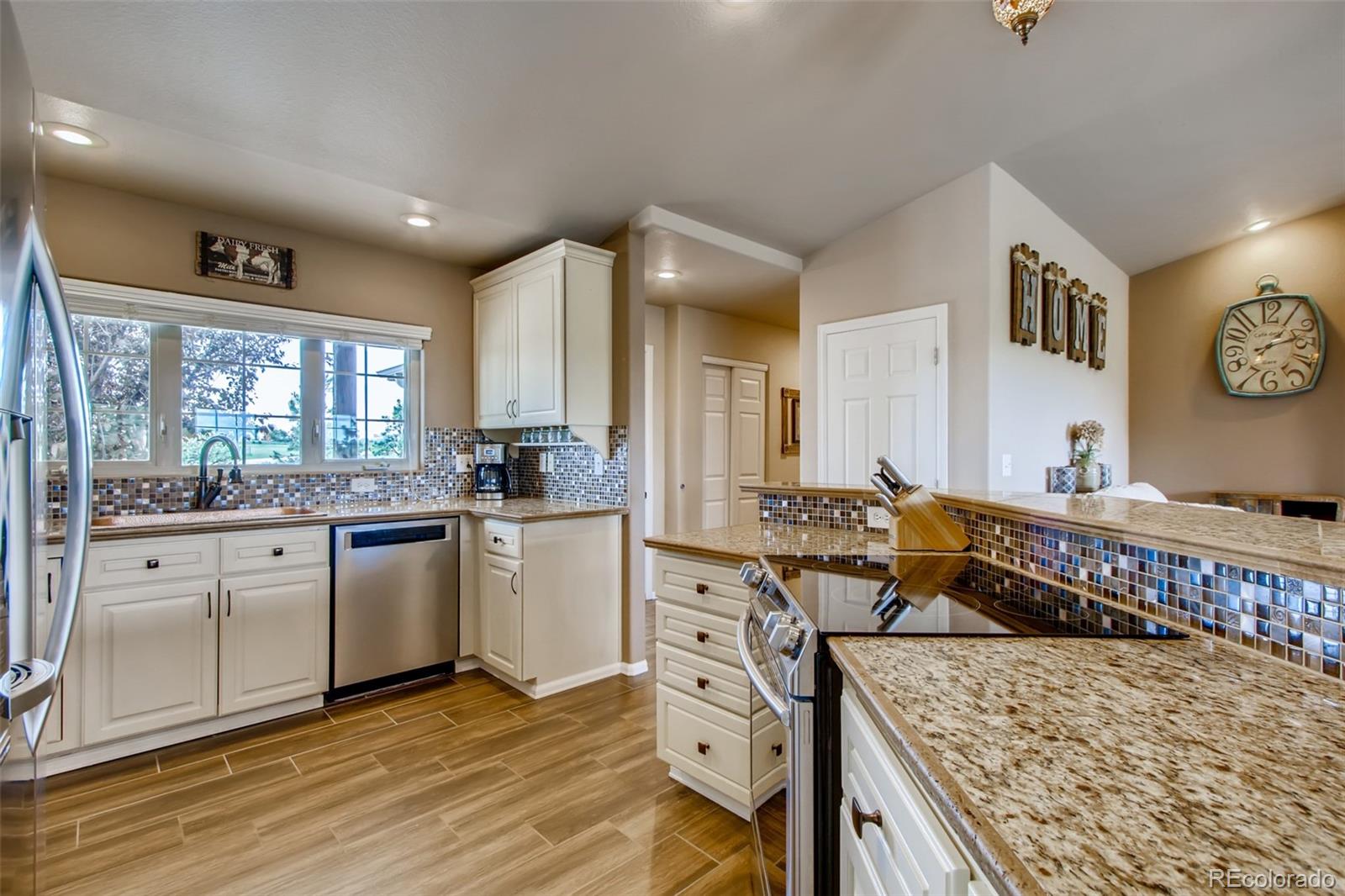 18030 Ranch Hand Road Peyton, CO 80831 - Photo 11 of 40 a open kitchen with stainless steel appliances granite countertop a stove a sink and a refrigerator