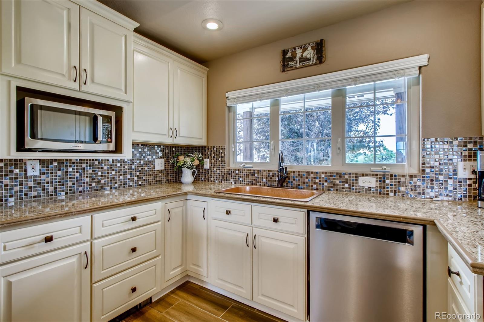 18030 Ranch Hand Road Peyton, CO 80831 - Photo 12 of 40 a kitchen with granite countertop cabinets stainless steel appliances a sink and window
