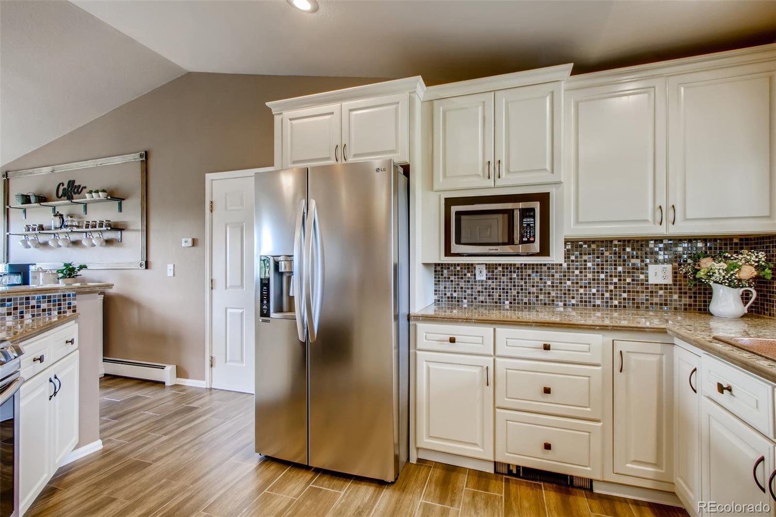 18030 Ranch Hand Road Peyton, CO 80831 - Photo 13 of 40 a kitchen with white cabinets and stainless steel appliances