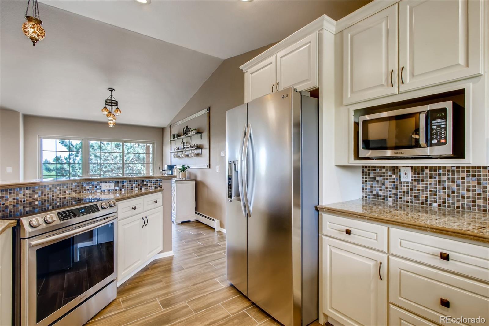18030 Ranch Hand Road Peyton, CO 80831 - Photo 14 of 40 a kitchen with cabinets stainless steel appliances a sink and wooden floor
