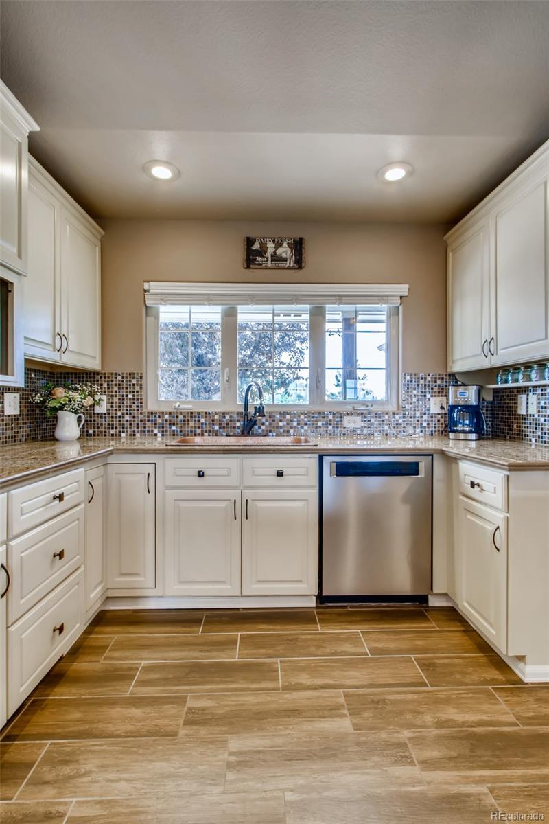 18030 Ranch Hand Road Peyton, CO 80831 - Photo 16 of 40 a kitchen with granite countertop a stove a sink and white cabinets