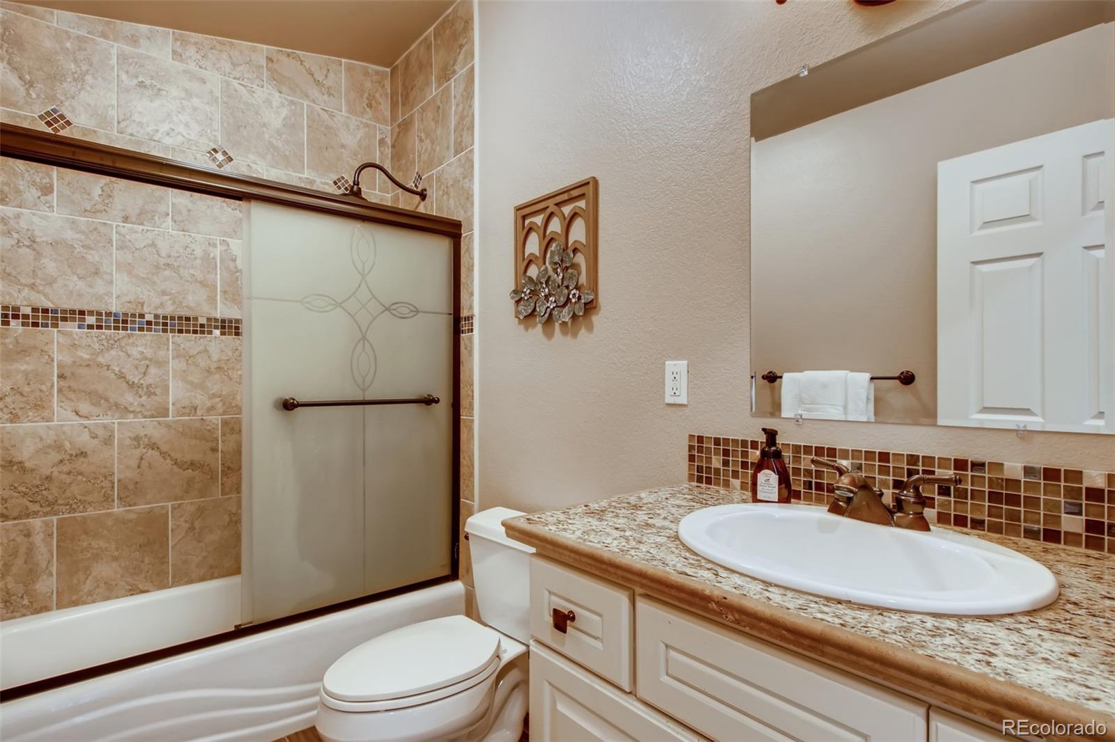 18030 Ranch Hand Road Peyton, CO 80831 - Photo 26 of 40 a bathroom with a granite countertop sink toilet and shower