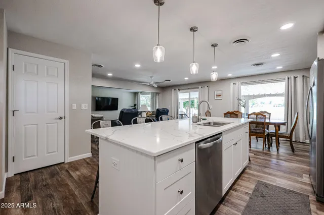 a kitchen with granite countertop a table chairs microwave and refrigerator