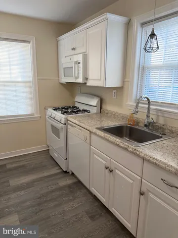 a kitchen with granite countertop white cabinets white appliances and a window