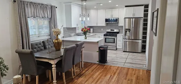 a kitchen with stainless steel appliances a refrigerator a stove a sink dishwasher and white cabinets with wooden floor