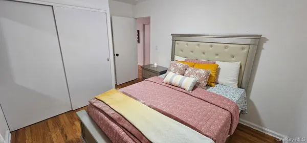 a bedroom with a bed a mirror on dresser and a wooden floor