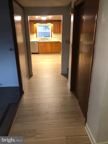 a view of a hallway with wooden floor and a living room