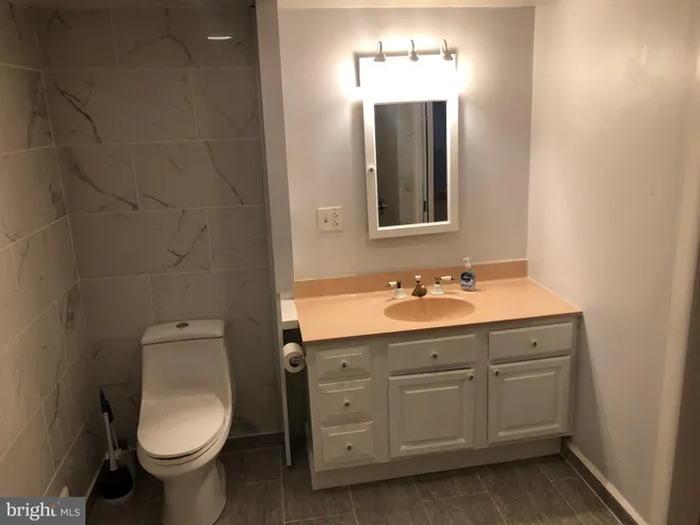 a bathroom with a granite countertop toilet sink and mirror