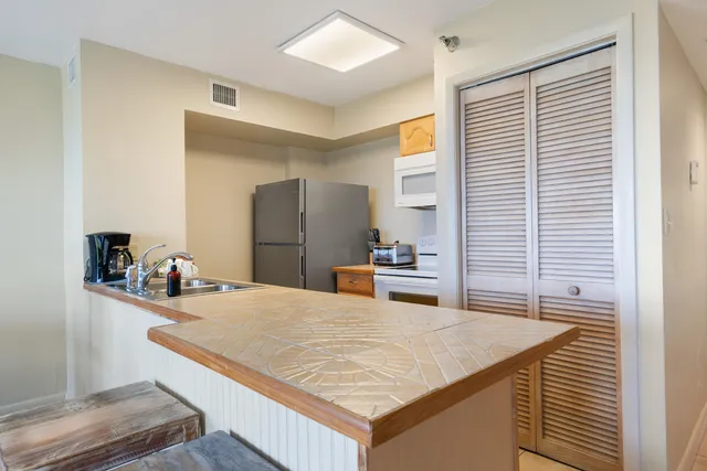 a kitchen with stainless steel appliances kitchen island granite countertop a refrigerator and a sink