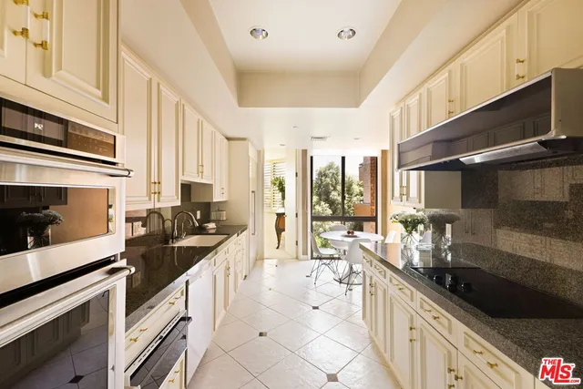 a kitchen with stainless steel appliances granite countertop a stove a sink and white cabinets