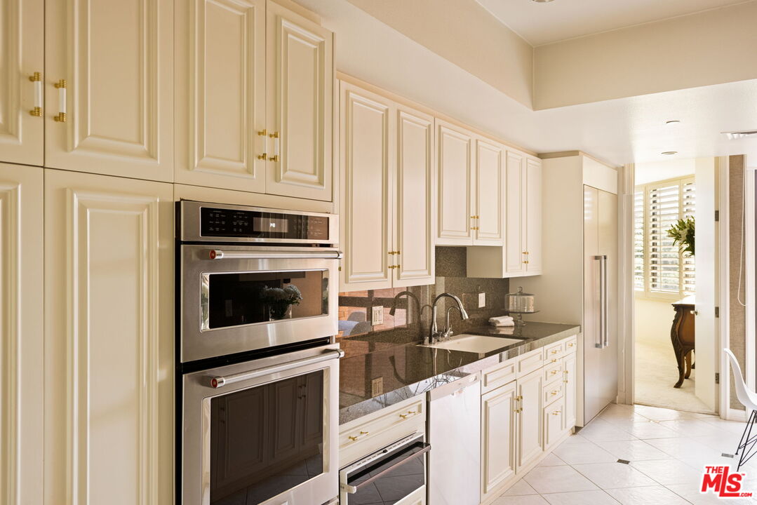 300 North Swall Drive, Unit 353 Beverly Hills, CA 90211 - Photo 16 of 31 a kitchen with granite countertop white cabinets and stainless steel appliances