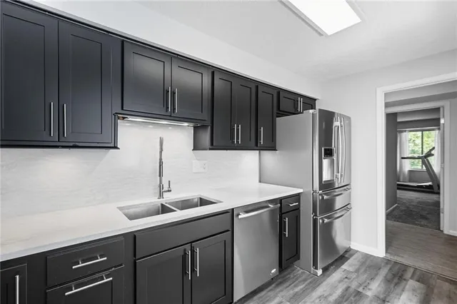 a kitchen with granite countertop stainless steel appliances a refrigerator and a sink