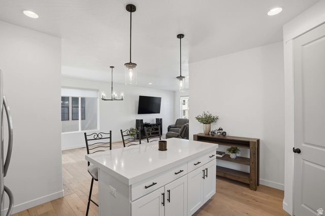 11531 Engelmann Drive Draper, UT 84020 - Photo 10 of 31 Kitchen island with white cabinetry and a light-toned countertop, featuring two pendant lights overhead