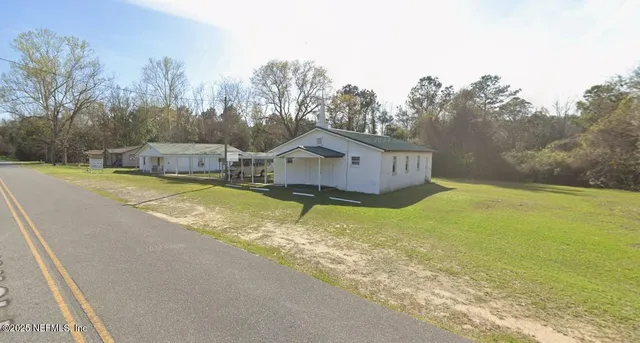 a view of a house with pool and a yard with trees in the background