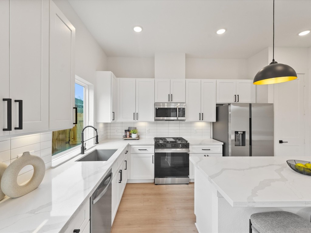 243 Rebecca Street, Unit F Houston, TX 77022 - Photo 10 of 26 a kitchen with stainless steel appliances a sink a stove a refrigerator a center island and cabinets