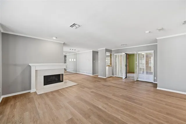 a view of an empty room with wooden floor fireplace and a window