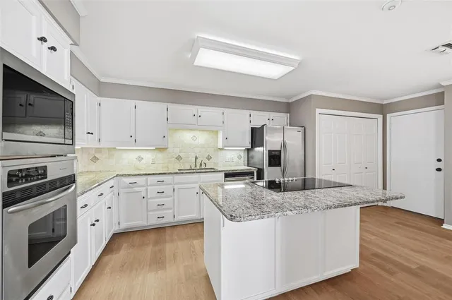 a kitchen with granite countertop a sink cabinets stainless steel appliances and wooden floor