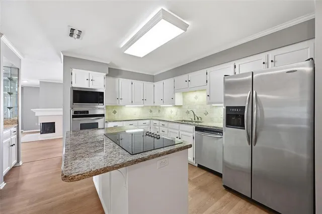 a kitchen with stainless steel appliances granite countertop a refrigerator a stove and a sink