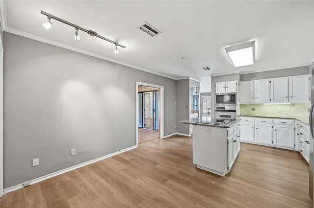 a kitchen with white cabinets and wooden floor