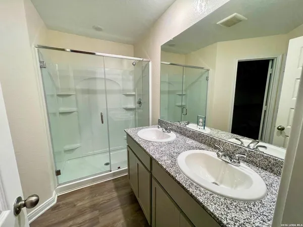 a bathroom with a granite countertop sink a mirror and shower