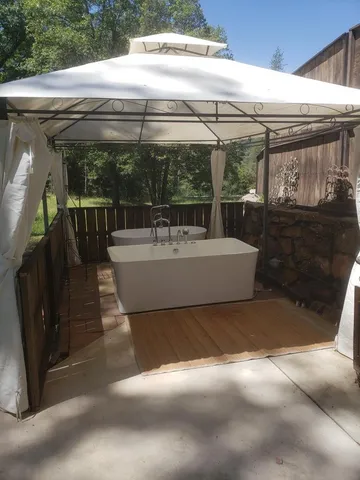 a view of a patio with a table and chairs under an umbrella with a small yard
