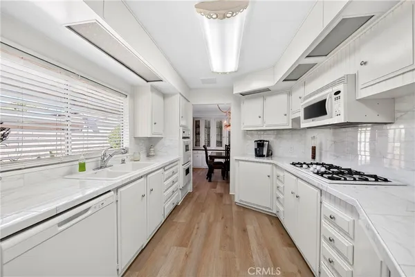 a large kitchen with stainless steel appliances granite countertop a lot of counter space and wooden floors