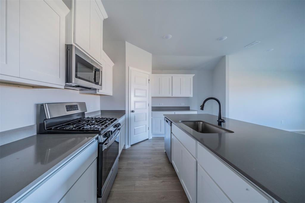 516 Ridgewood Drive Van Alstyne, TX 75495 - Photo 6 of 25 a kitchen with stainless steel appliances granite countertop a sink stove top oven and cabinets