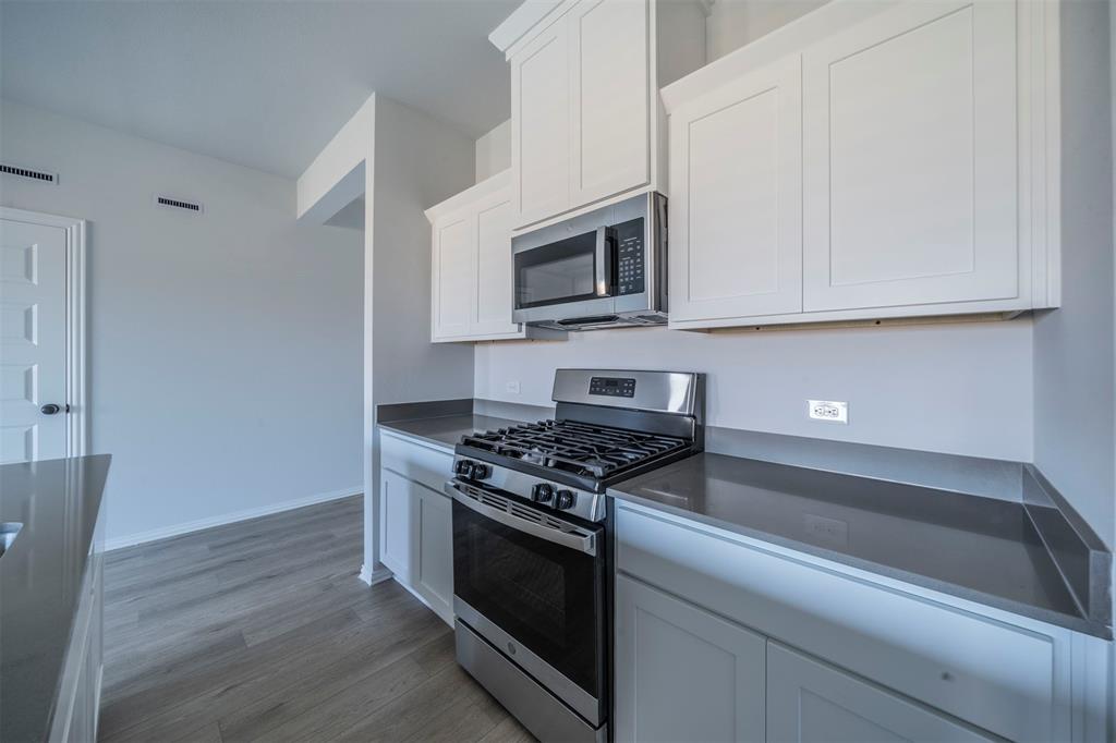 516 Ridgewood Drive Van Alstyne, TX 75495 - Photo 7 of 25 a kitchen with granite countertop cabinets stainless steel appliances and wooden floor