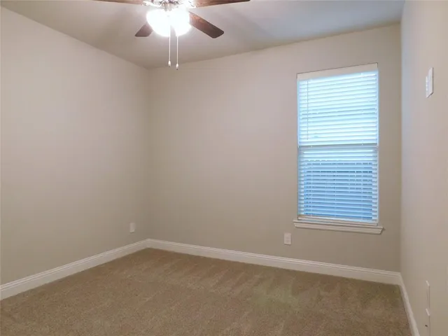 an empty room with a window and a fan