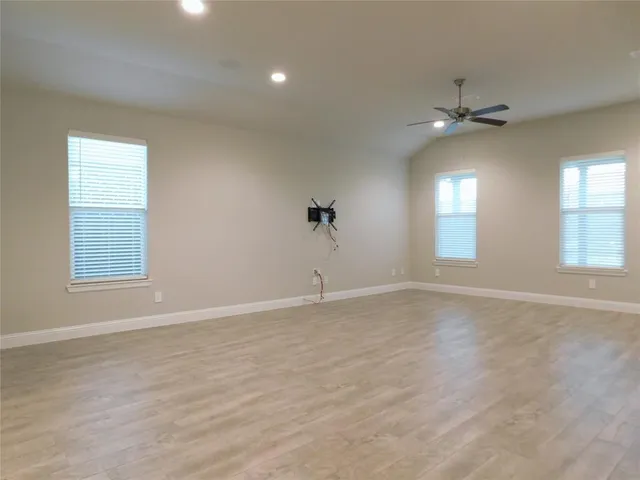 an empty room with windows and ceiling fan