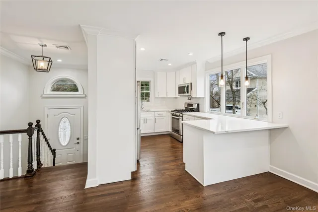 a kitchen with white cabinets and window