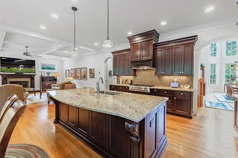 a view of a kitchen with kitchen island a large window cabinets a sink and stainless steel appliances