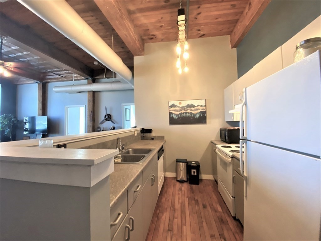 158-160 Chestnut Street, Unit 2F Springfield, MA 01103 - Photo 5 of 12 a kitchen with stainless steel appliances granite countertop a sink a stove a refrigerator with white cabinets and wooden floor