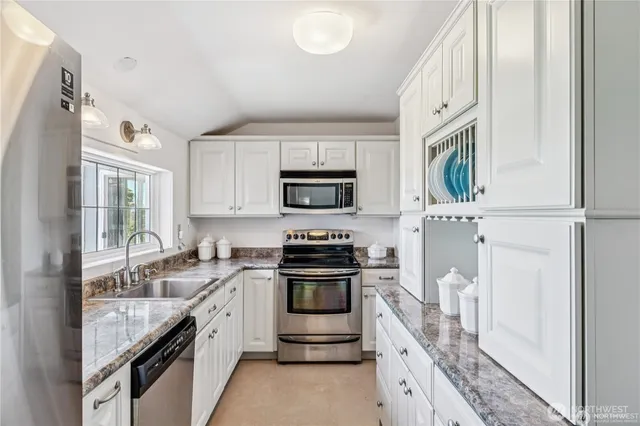 a kitchen with granite countertop a stove sink and a microwave