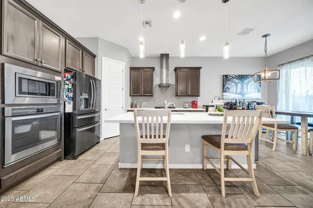 a kitchen with stainless steel appliances kitchen island granite countertop a refrigerator and microwave