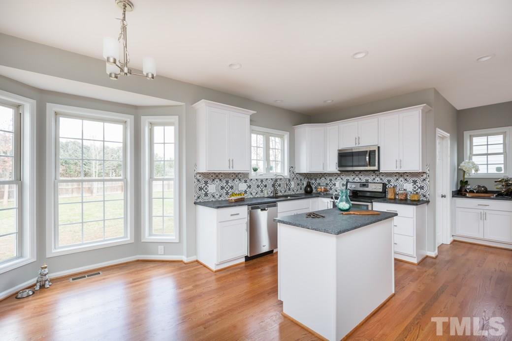 232 Seastone Street Raleigh, NC 27603 - Photo 8 of 20 a kitchen with stainless steel appliances granite countertop a stove top oven a sink dishwasher a refrigerator and white cabinets with wooden floor