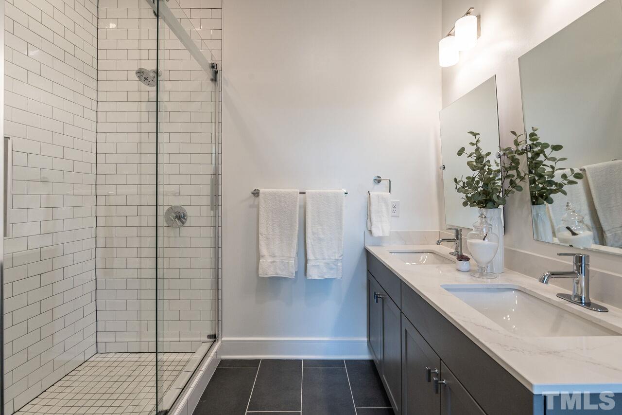 615 Daniels Street, Unit 318 Raleigh, NC 27605 - Photo 15 of 26 a bathroom with a double vanity sink a shower and a mirror