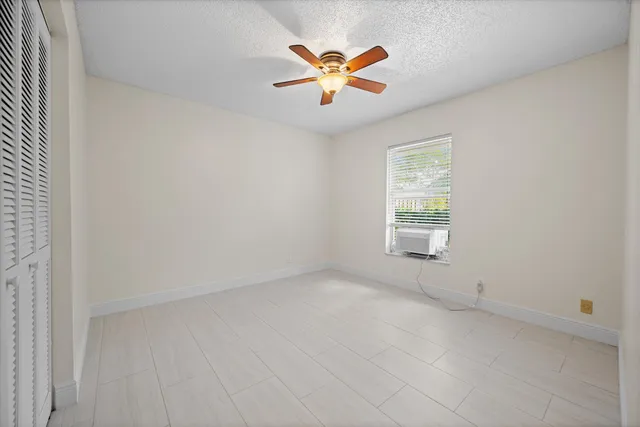 an empty room with ceiling fan and window