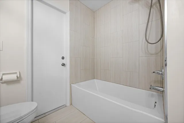 a white bath tub sitting next to a white toilet and a shower