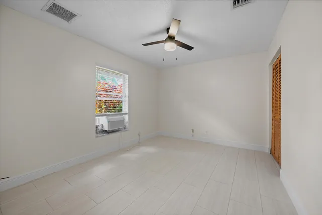 an empty room with windows and fan