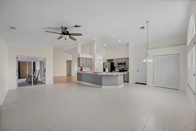 a living room with stainless steel appliances kitchen island furniture and a ceiling fan