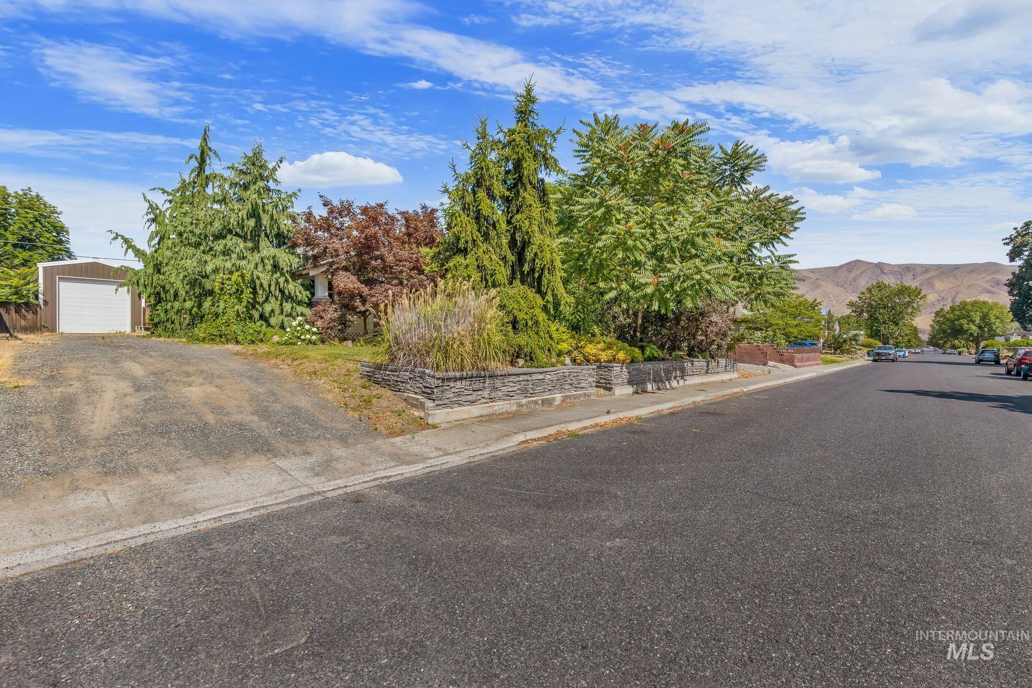 928 3rd Street Clarkston, WA 99403 - Photo 44 of 44 Expansive gravel driveway leading to a detached metal garage with a white roll-up door