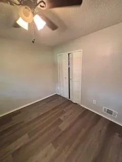 a view of a room with wooden floor and a ceiling fan