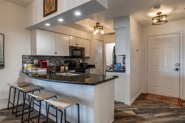 a kitchen with kitchen island granite countertop a sink cabinets and appliances