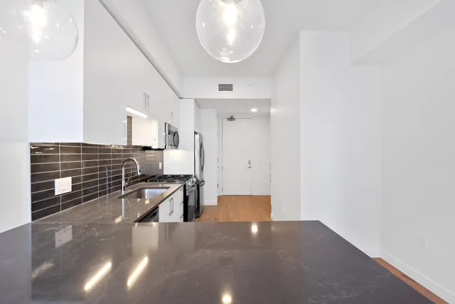 a view of an empty room with wooden floor and door