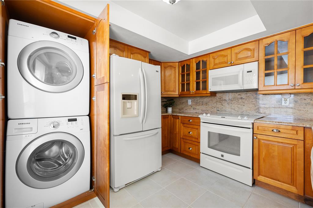 9000 Commodore Drive, Unit 604 Seminole, FL 33776 - Photo 12 of 50 a kitchen with stainless steel appliances granite countertop a washer and dryer