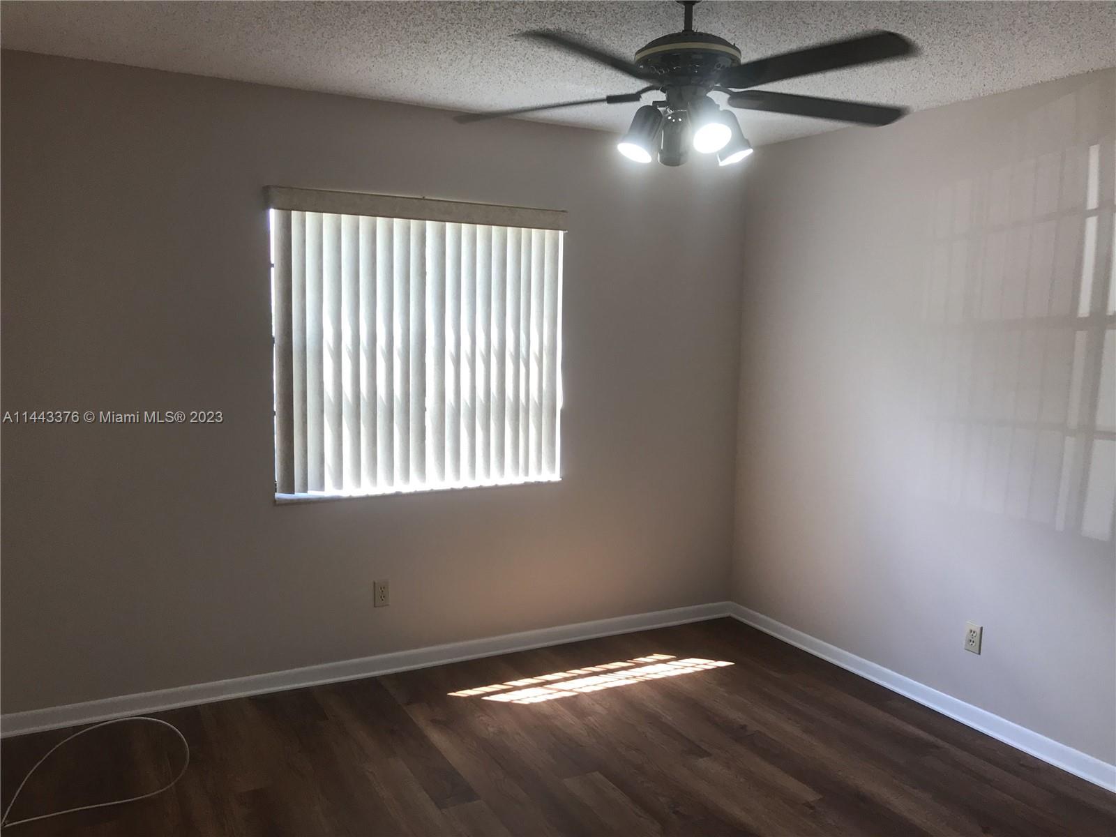 801 Pinecrest Circle, Unit E Jupiter, FL 33458 - Photo 12 of 18 a view of an empty room with window and chandelier fan